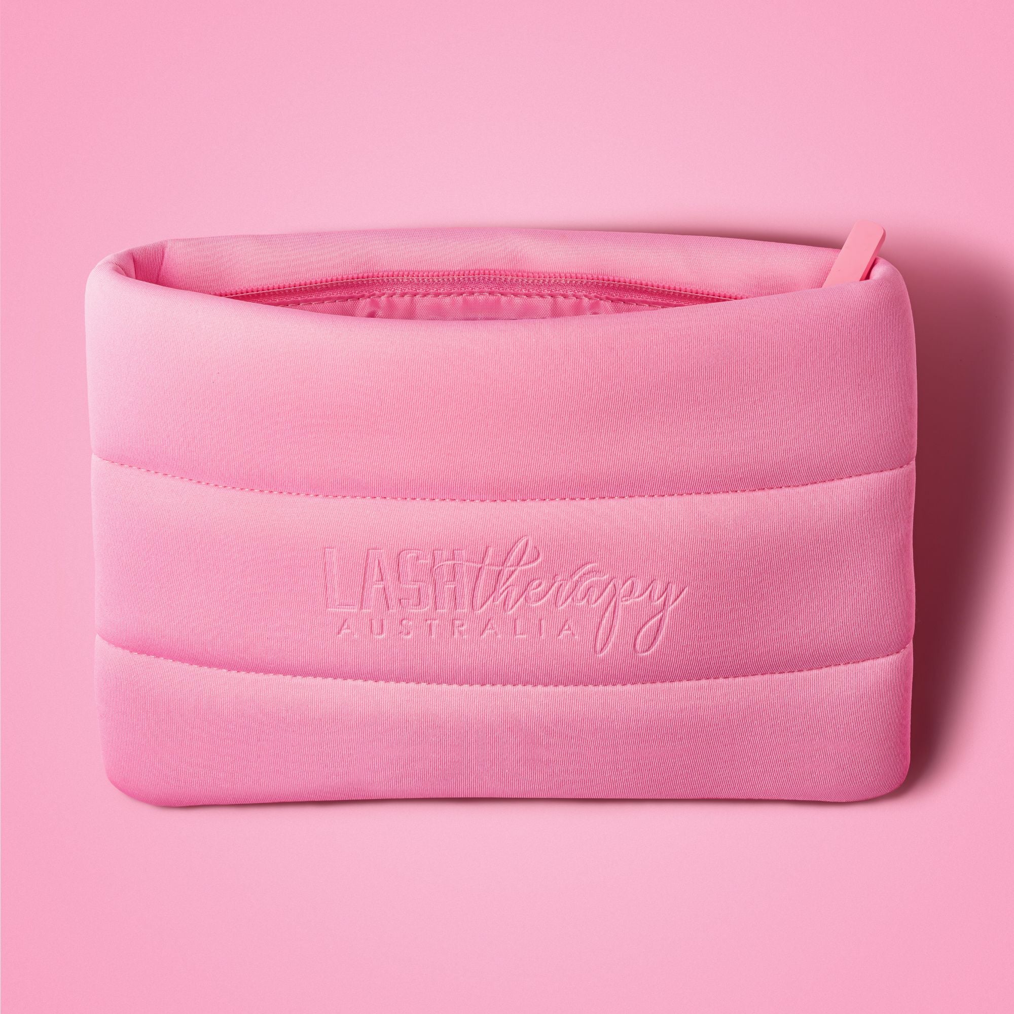 Hot pink Lash Therapy Australia cosmetic bag on pink background